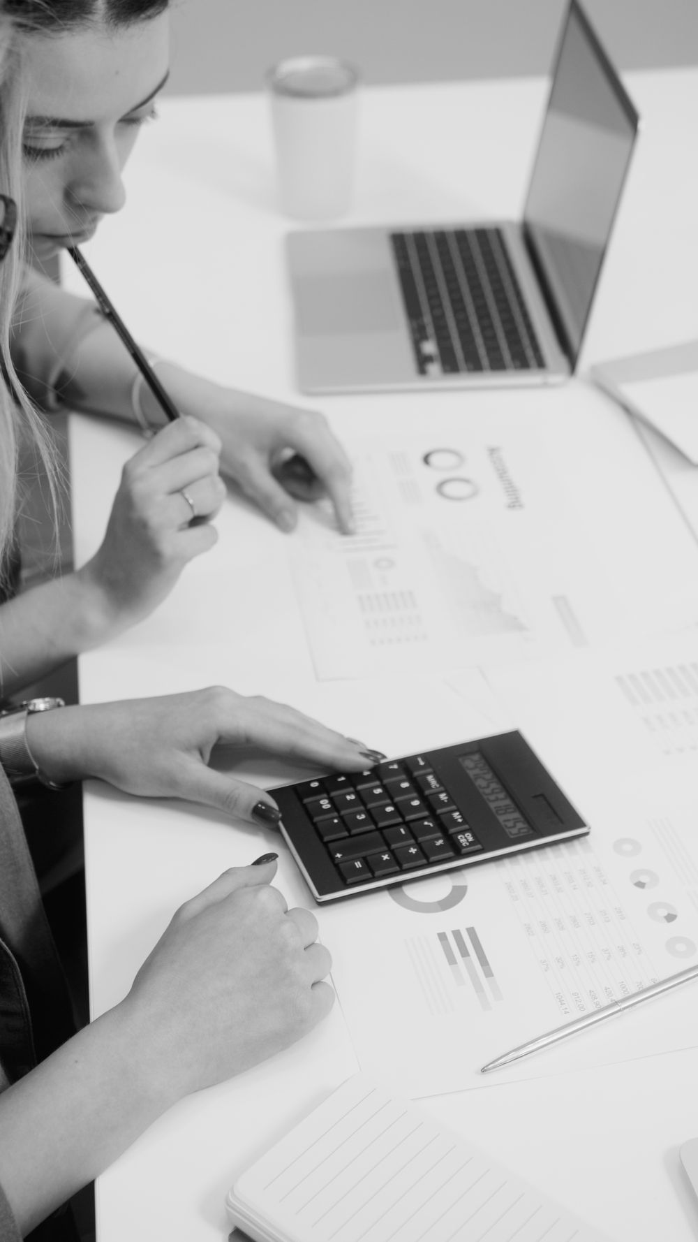 Two women reviewing financial reports with a calculator